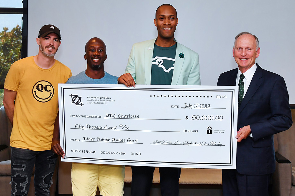 Scott Wooten, Jerri Shephard ‘13 and Chris Moxley ‘03, presented a $50,000 check for the Niner Nation Unites Fund to Chancellor Dubois